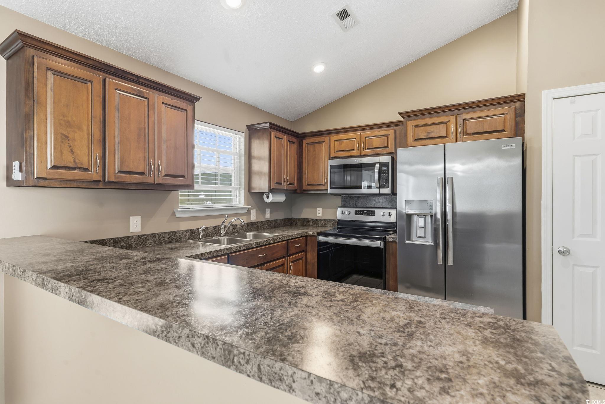 1007 Green Fir Loop Conway, SC 29527 - Photo 16 of 38 Kitchen featuring appliances with stainless steel finishes, dark countertops, lofted ceiling, recessed lighting, and a peninsula