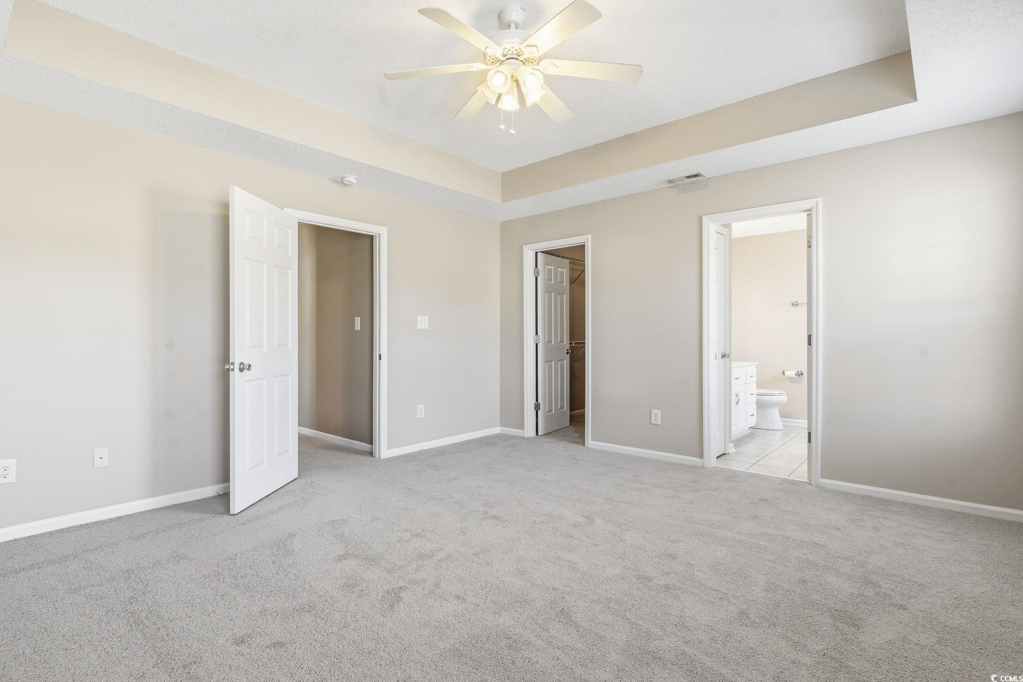 1007 Green Fir Loop Conway, SC 29527 - Photo 25 of 38 Unfurnished bedroom featuring a tray ceiling, light carpet, a walk in closet, and a ceiling fan