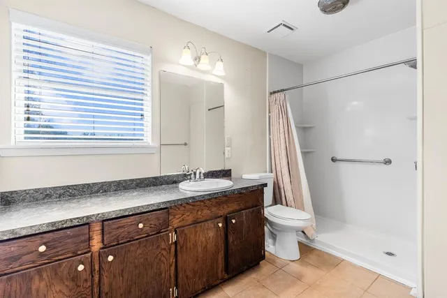 an empty room with windows and chandelier fan