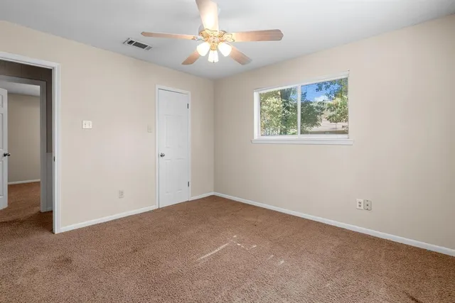 a view of an empty room with a chandelier fan