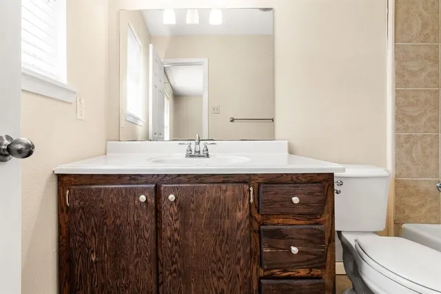 a bathroom with a toilet sink vanity and mirror