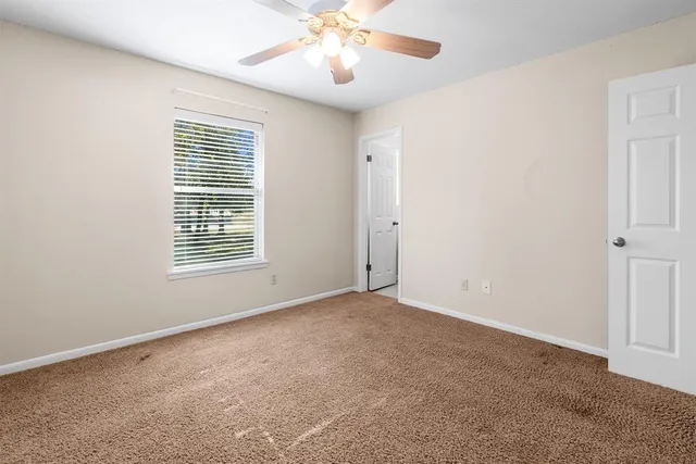 a view of an empty room and chandelier fan