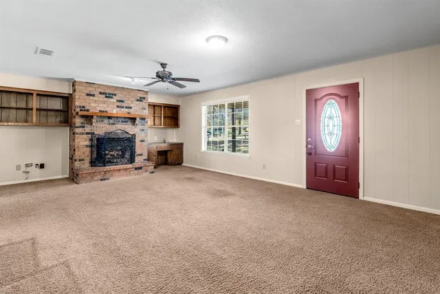 an empty room with windows fireplace and fans