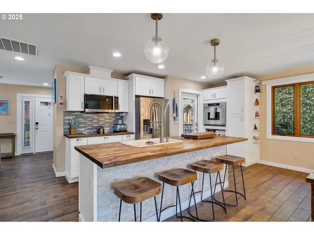 a kitchen with stainless steel appliances kitchen island granite countertop a table chairs sink and cabinets