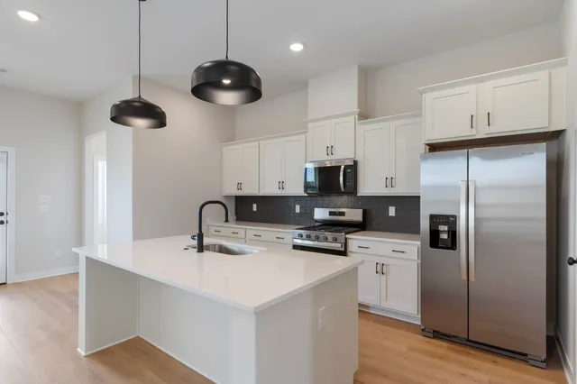 a kitchen with stainless steel appliances a refrigerator a sink a stove a microwave and cabinets