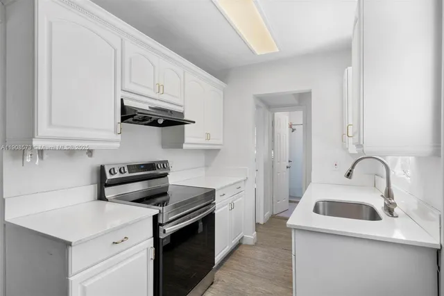 a kitchen with stainless steel appliances granite countertop a sink dishwasher a stove and a refrigerator with wooden cabinets