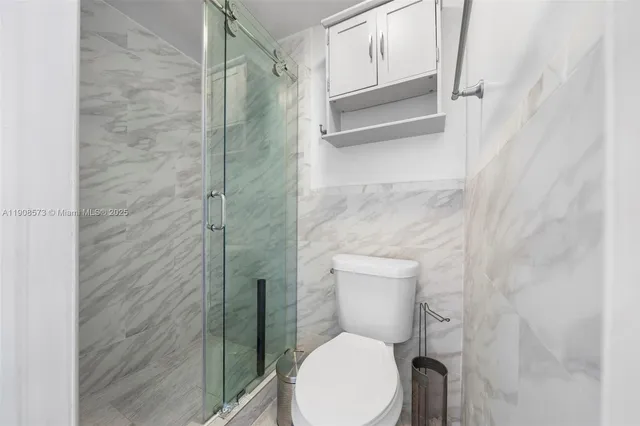 a white toilet sitting next to a shower