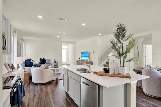 a kitchen with a sink dishwasher a dining table and chairs with wooden floor