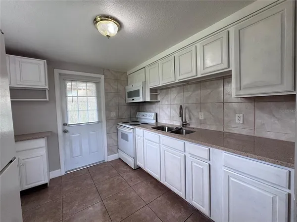 a kitchen with granite countertop white cabinets and stainless steel appliances