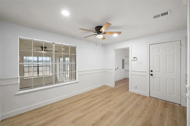 a view of empty room with wooden floor and fan