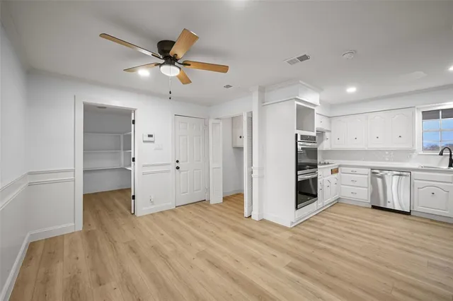 a view of kitchen and empty room with wooden floor