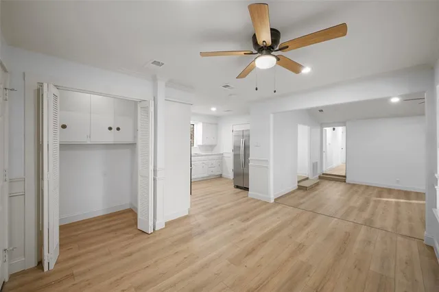 a view of empty room with wooden floor and ceiling fan