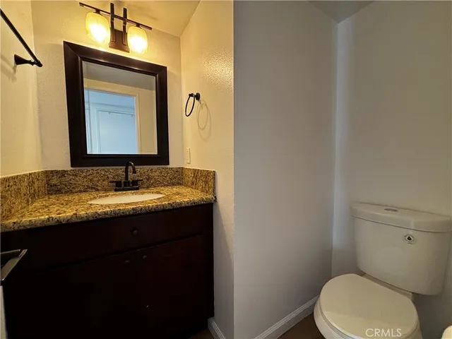 a bathroom with a granite countertop toilet a sink and mirror