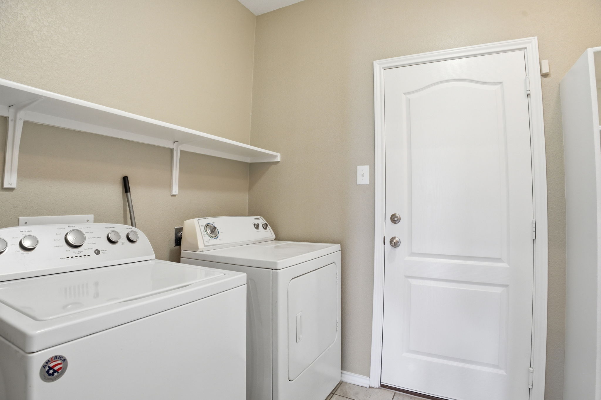670 Landon Samuel Loop Pflugerville, TX 78660 - Photo 19 of 22 Laundry area featuring a pair of white appliances, wall-mounted shelving, and a paneled door