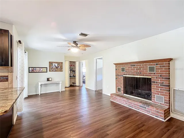 a view of an empty room fire place and wooden floor