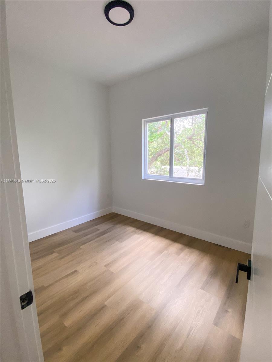 2121 Northwest 45th Street, Unit 2123 Miami, FL 33142 - Photo 6 of 24 wooden floor in an empty room with a window