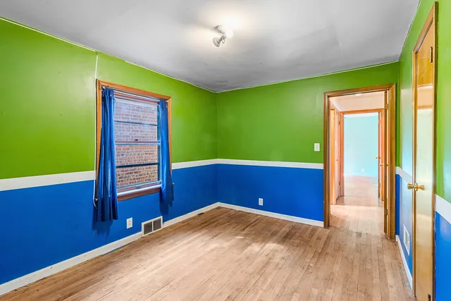 a view of empty room with window and wooden floor