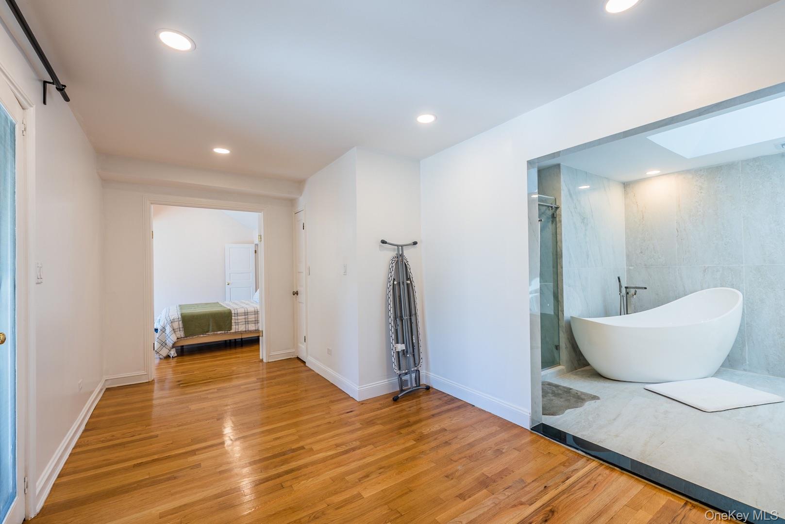 530 South Centre Island Road Centre Island, NY 11771 - Photo 19 of 32 Ensuite bathroom with a freestanding bath, light wood-style flooring, tile walls, a skylight, and recessed lighting