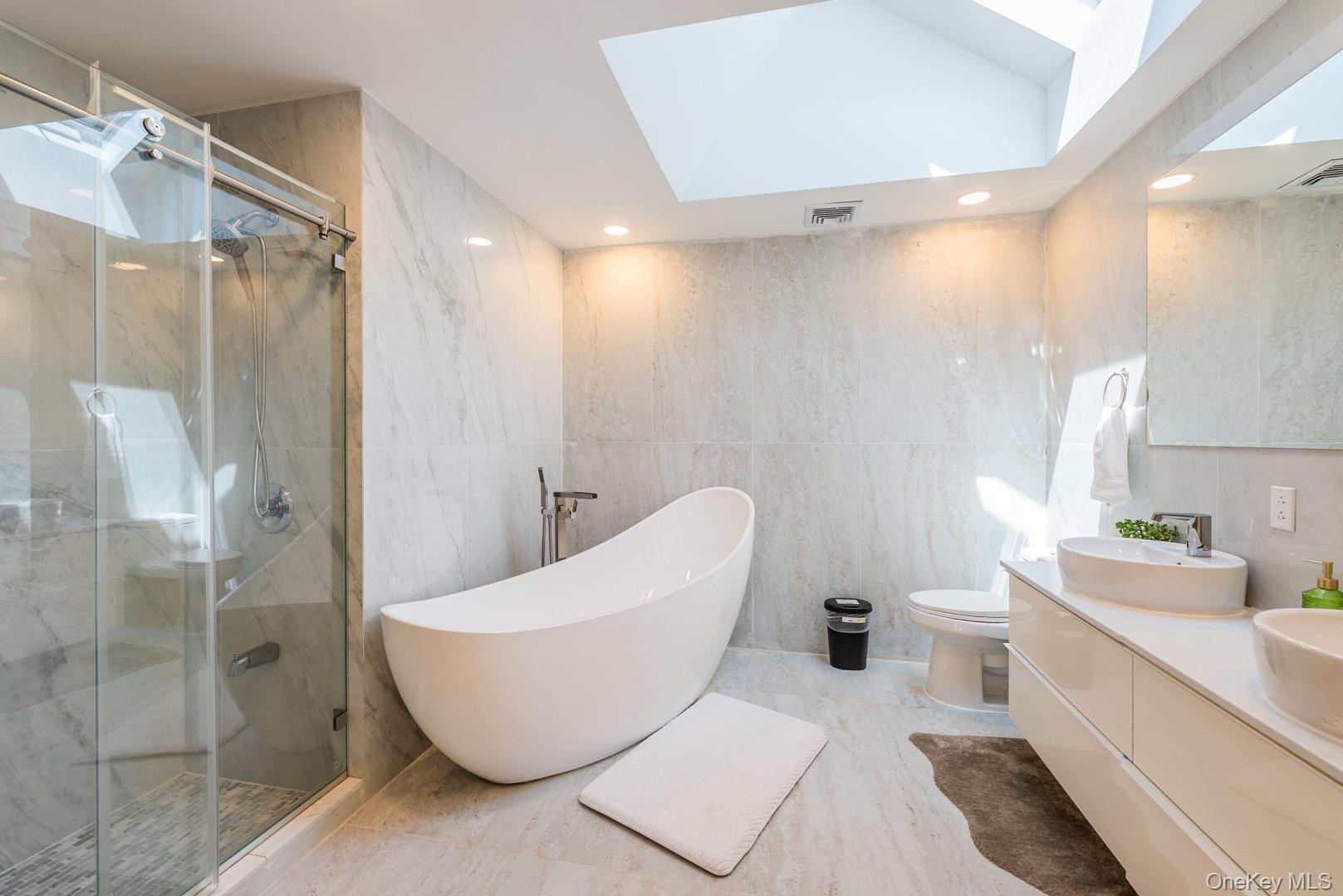 530 South Centre Island Road Centre Island, NY 11771 - Photo 20 of 32 Bathroom with tile walls, a soaking tub, a marble finish shower, a skylight, and recessed lighting