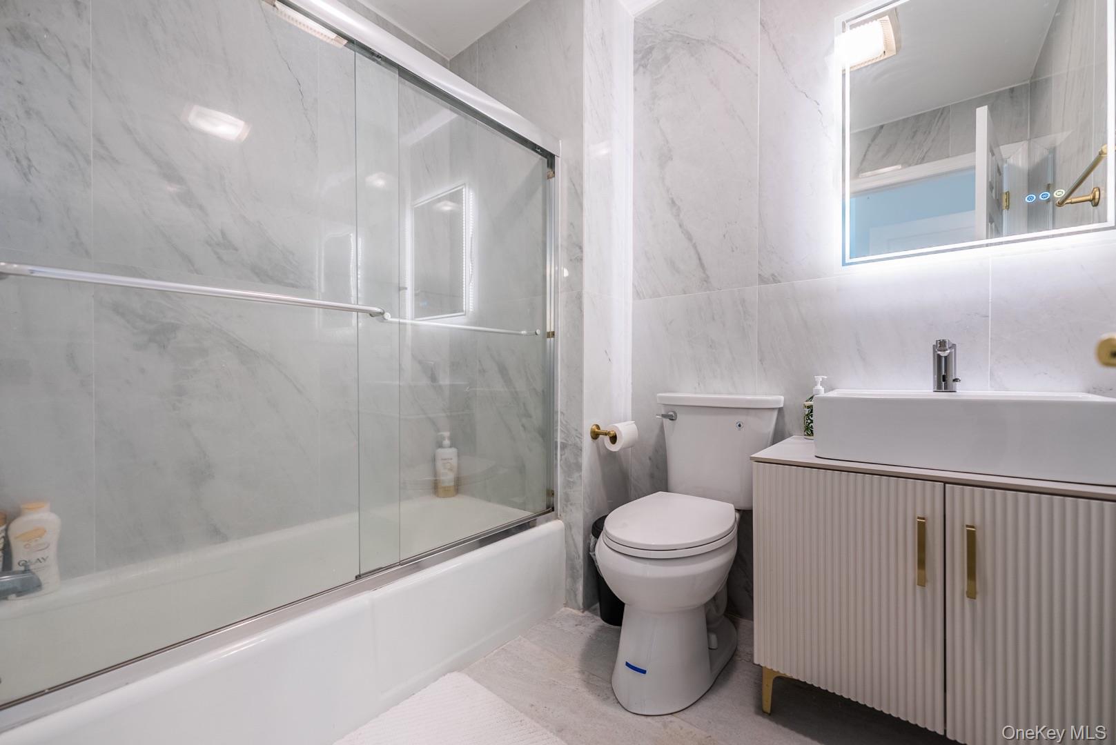 530 South Centre Island Road Centre Island, NY 11771 - Photo 28 of 32 Bathroom featuring shower / bath combination with glass door, vanity, and tile walls