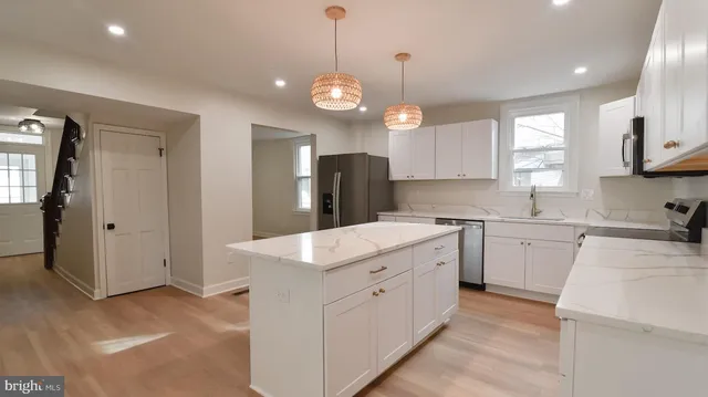 a kitchen with a sink and dishwasher with white cabinets