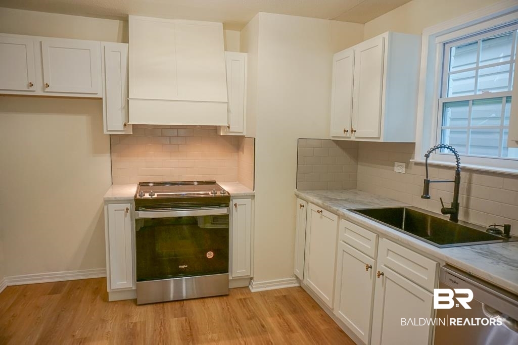 4734 Kirkwell Drive Mobile, AL 36619 - Photo 7 of 18 Kitchen with white cabinets, stainless steel appliances, light hardwood / wood-style floors, sink, and decorative backsplash