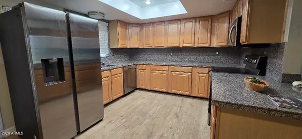 a kitchen with granite countertop stainless steel appliances a refrigerator a sink a stove and cabinets