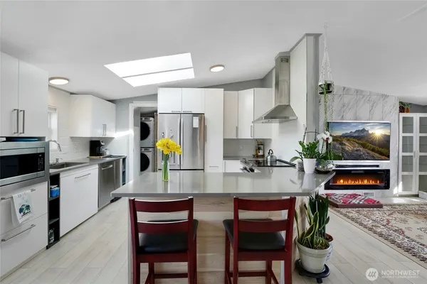 a kitchen with stainless steel appliances kitchen island granite countertop a dining table chairs and white cabinets