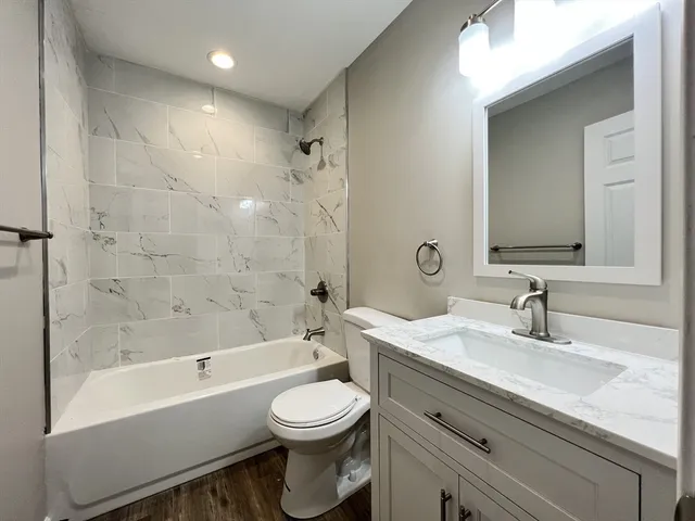 a bathroom with a bathtub shower sink vanity mirror and toilet
