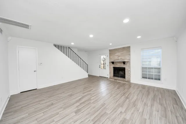 an empty room with chandelier fan and windows