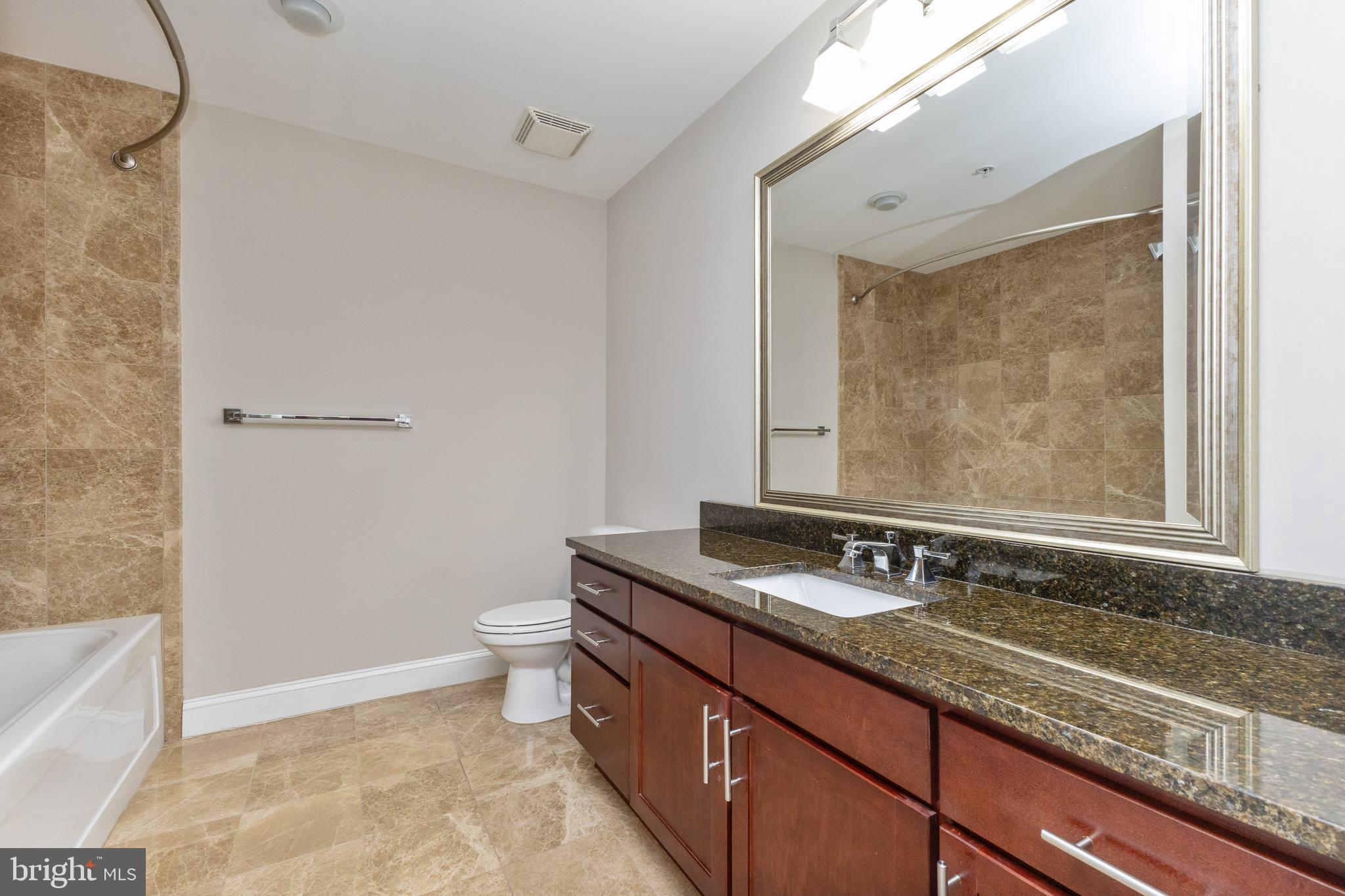 6301 Edsall Road, Unit 513 Alexandria, VA 22312 - Photo 24 of 38 a bathroom with a granite countertop sink a toilet a mirror and bathtub