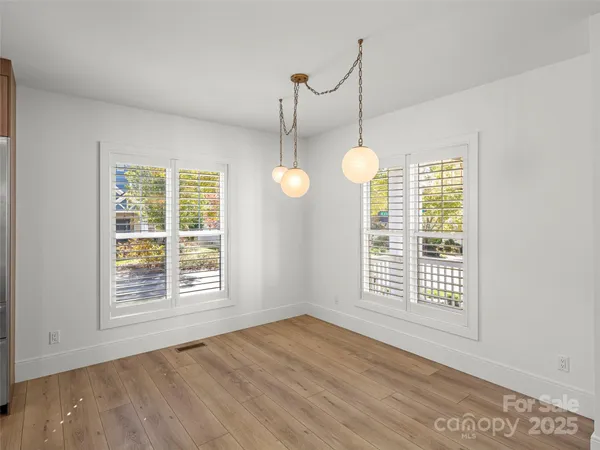 a view of an empty room with wooden floor and windows