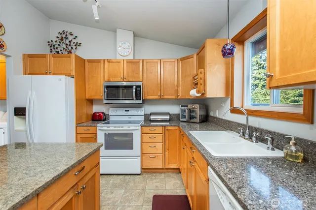 a kitchen with granite countertop a sink stove and refrigerator