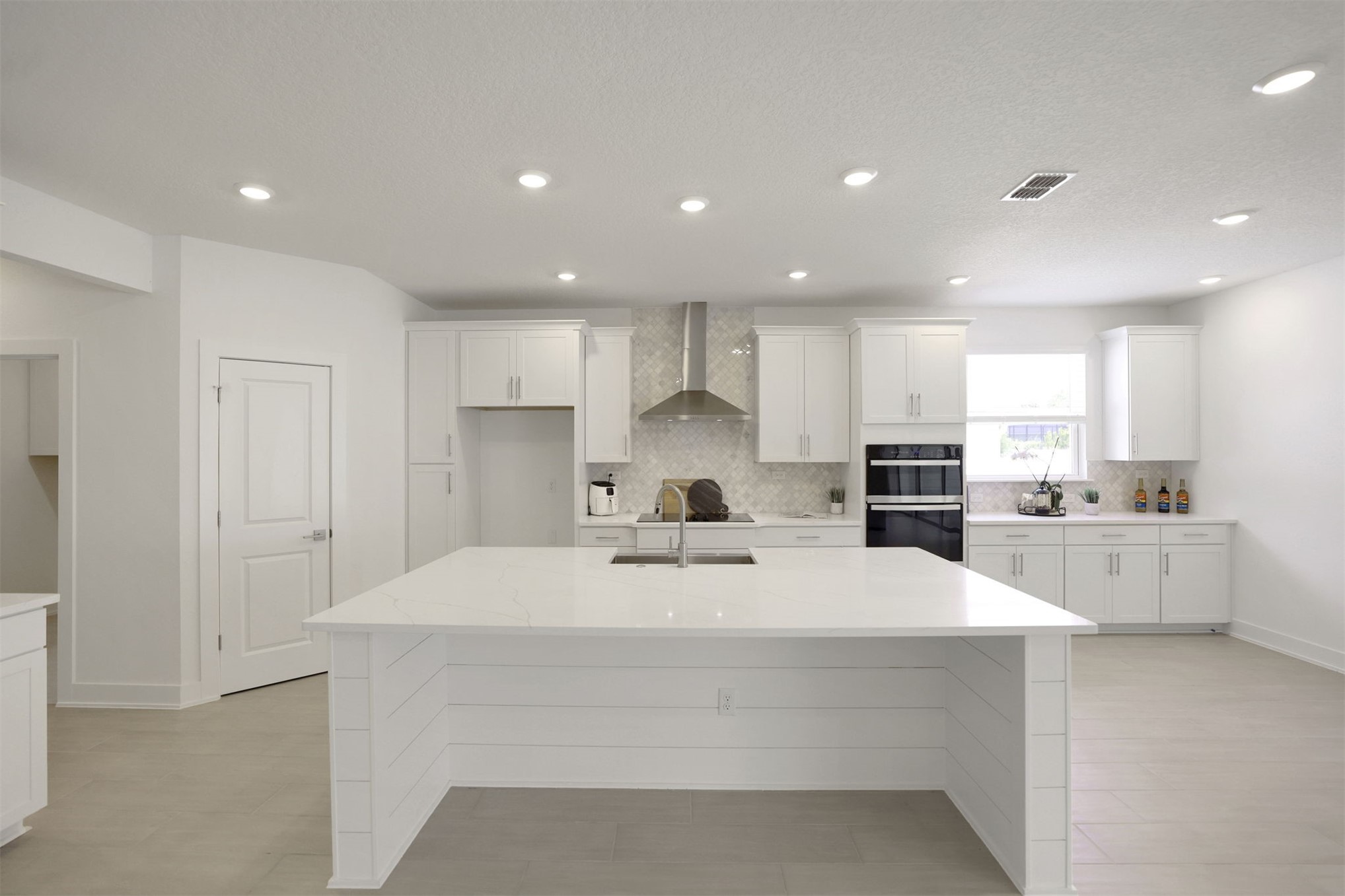 96040 Pirates Bluff Road Yulee, FL 32097 - Photo 2 of 38 a large white kitchen with kitchen island a sink a center island stainless steel appliances and a cabinets