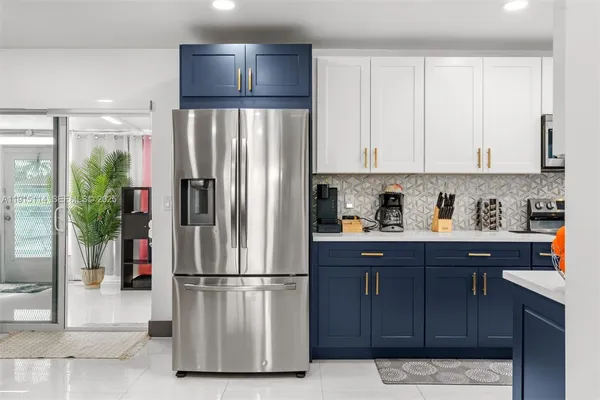 a kitchen with stainless steel appliances granite countertop a refrigerator a sink and white cabinets