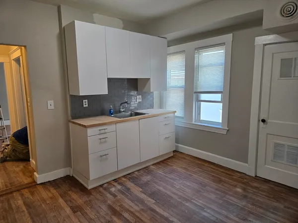 a kitchen with a sink wooden floor and a stove top oven