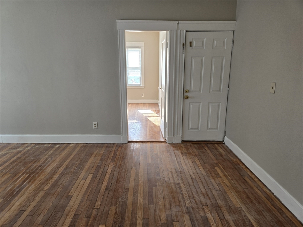 654 Metropolitan Avenue, Unit 4 Boston, MA 02136 - Photo 10 of 16 a view of an empty room with wooden floor and a window