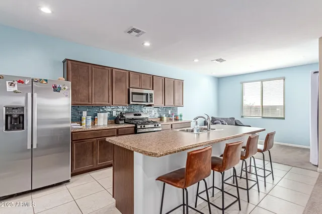 a kitchen with stainless steel appliances granite countertop a stove top oven a sink dishwasher and a refrigerator with wooden cabinets