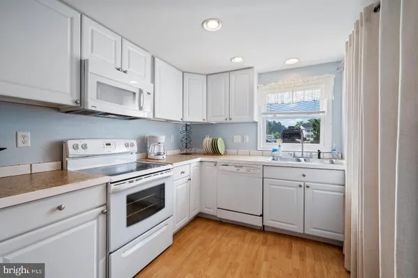a kitchen with granite countertop white cabinets and white appliances