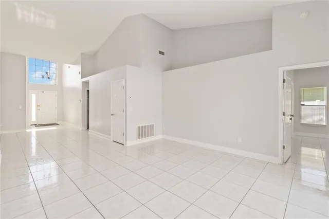 an empty room with chandelier fan and windows