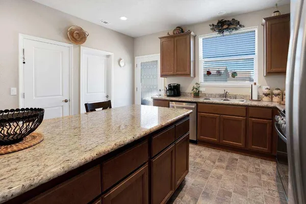 a kitchen with stainless steel appliances granite countertop a sink a stove and a wooden cabinets