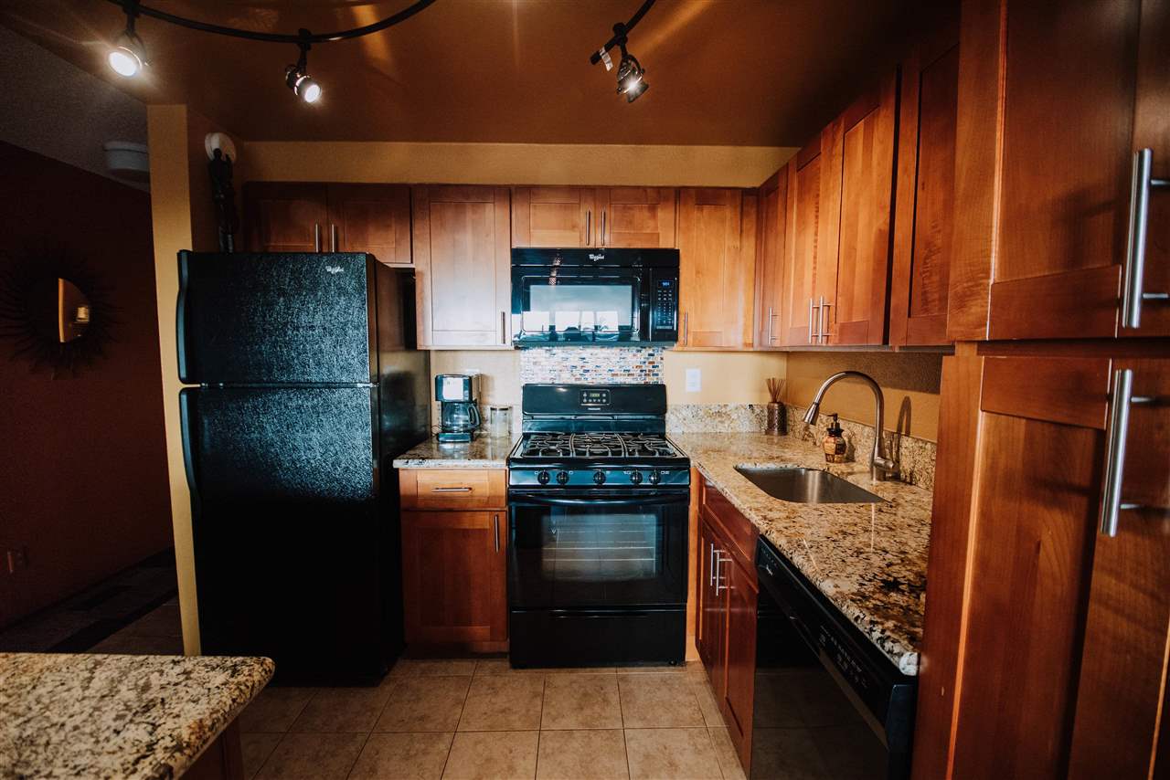 a kitchen with stainless steel appliances granite countertop a refrigerator a sink and a stove