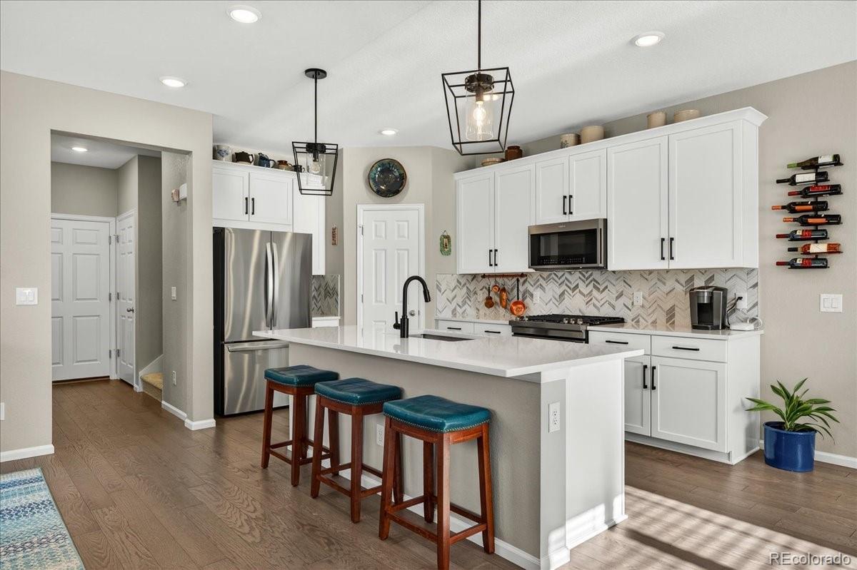 9793 Banner Peak Loop Littleton, CO 80125 - Photo 5 of 42 a kitchen with stainless steel appliances kitchen island a refrigerator a stove a sink a dining table and chairs