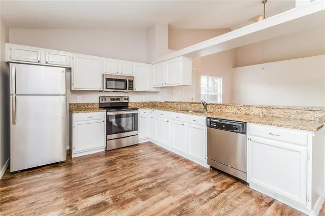 a kitchen with granite countertop a refrigerator stove top oven and sink