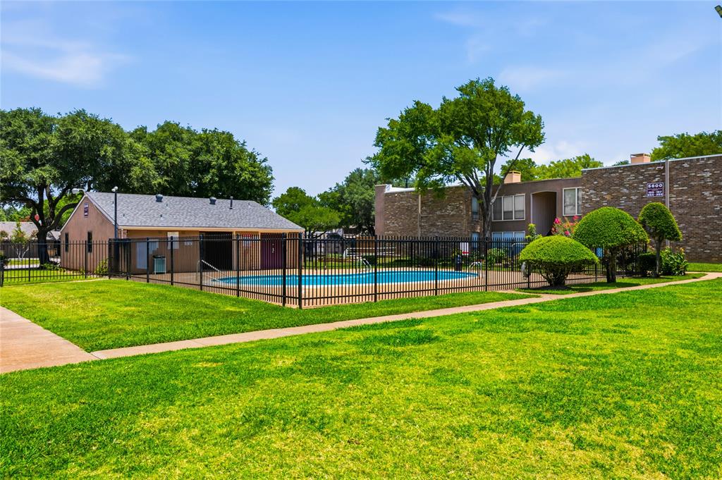 5540 Boca Raton Boulevard, Unit 181 Fort Worth, TX 76112 - Photo 6 of 21 Fenced swimming pool area with a surrounding lawn, mature trees, and a low-rise building featuring brick and stucco finishes