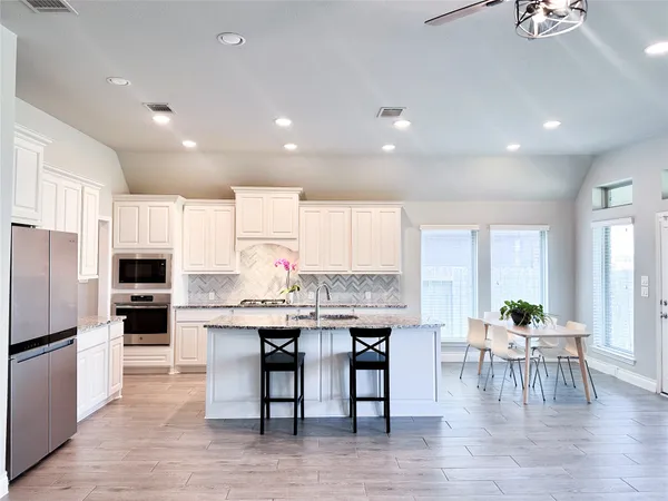 a large kitchen with kitchen island a dining table chairs and a refrigerator