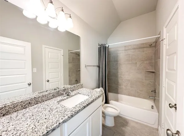 a bathroom with a granite countertop sink a toilet and bathtub