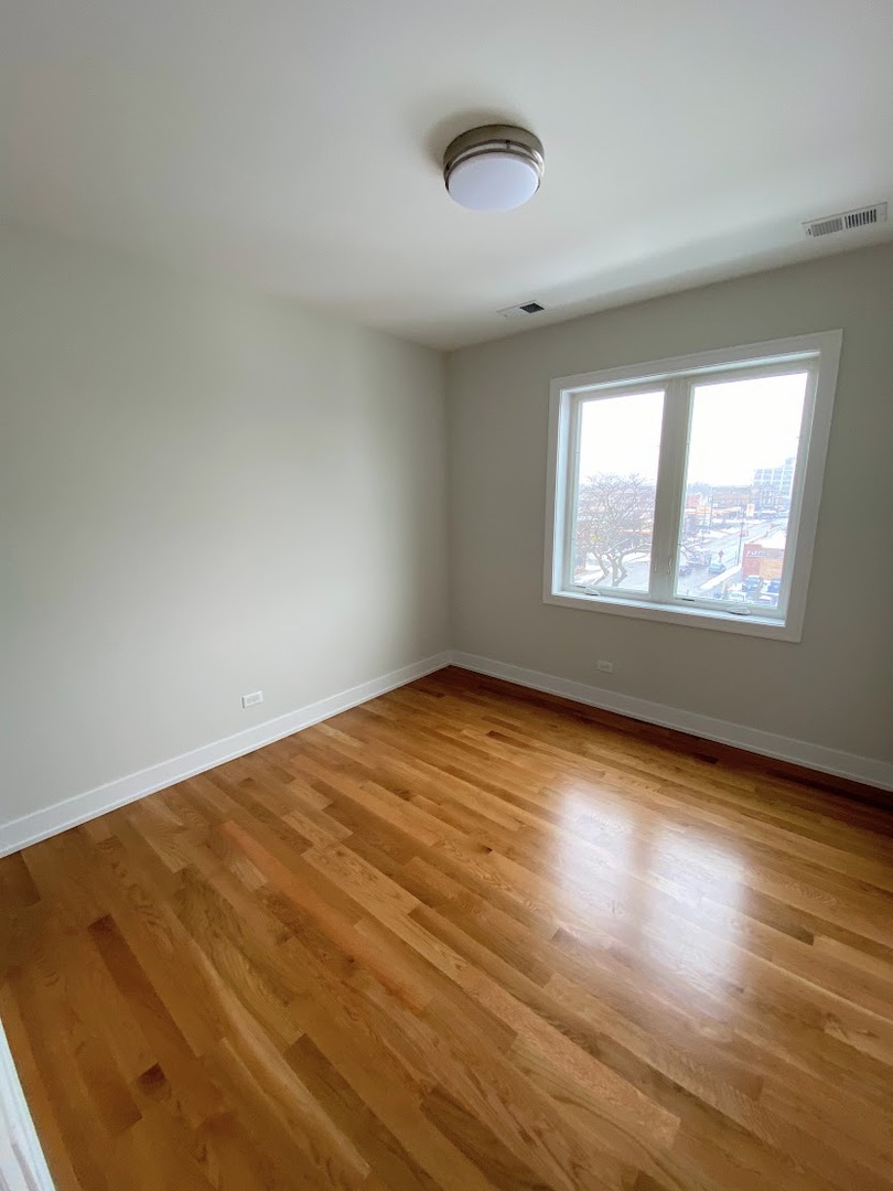 3203 North Ridgeway Avenue, Unit 2B Chicago, IL 60618 - Photo 13 of 17 an empty room with wooden floor and windows