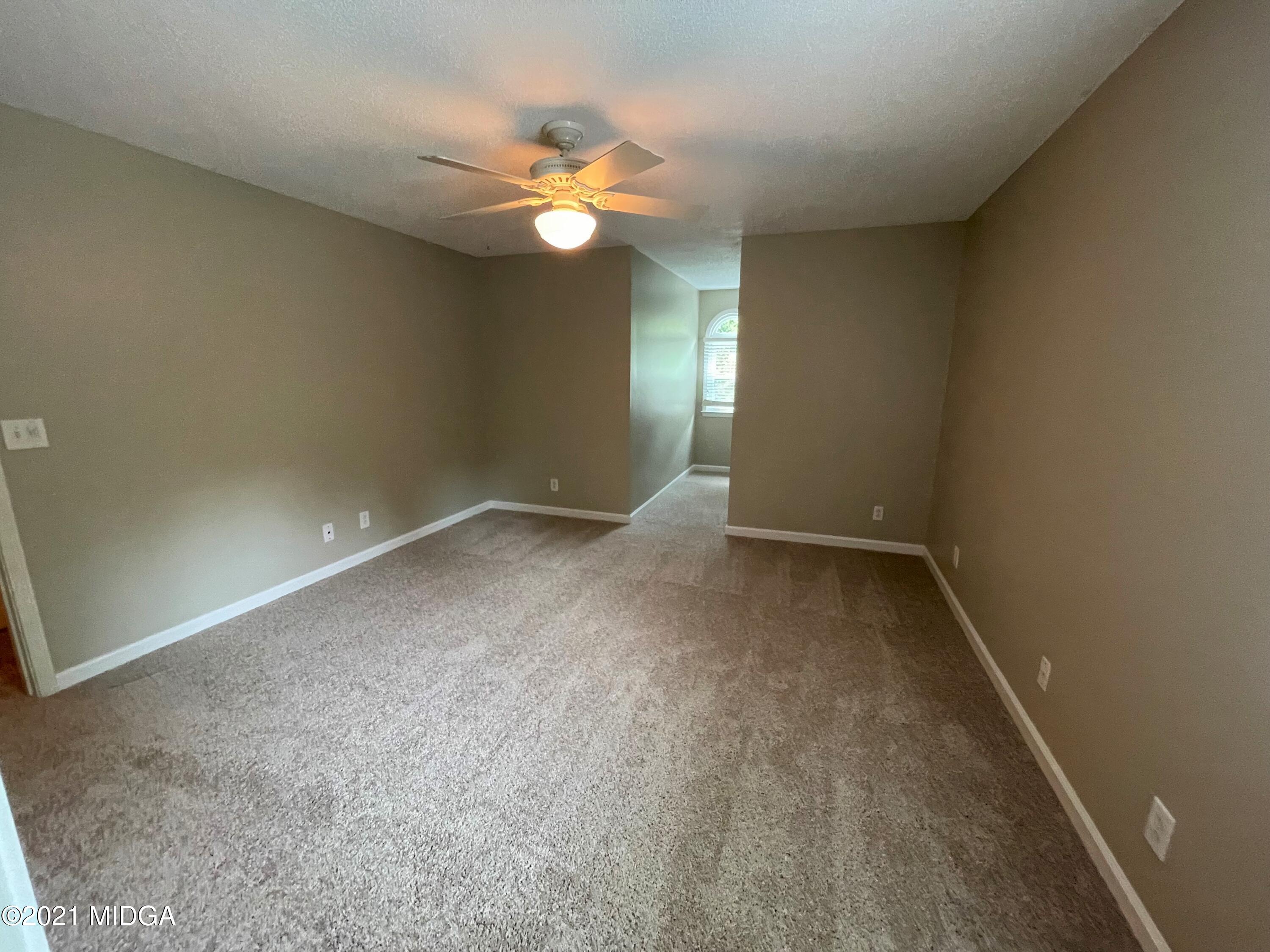 253 Ridge Crest Drive Macon, GA 31210 - Photo 10 of 16 an empty room with a chandelier fan and windows