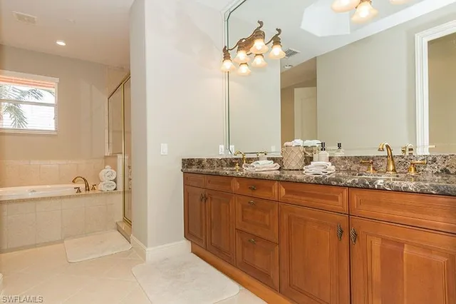 a bathroom with a granite countertop sink a large mirror and a bathtub